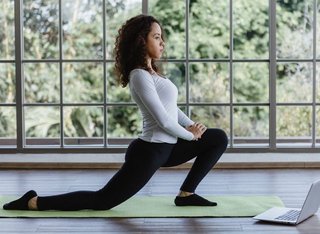 Νεαρή γυναίκα που κάνει μπροστινή Lunges ή Squat Asiseer στο σπίτι